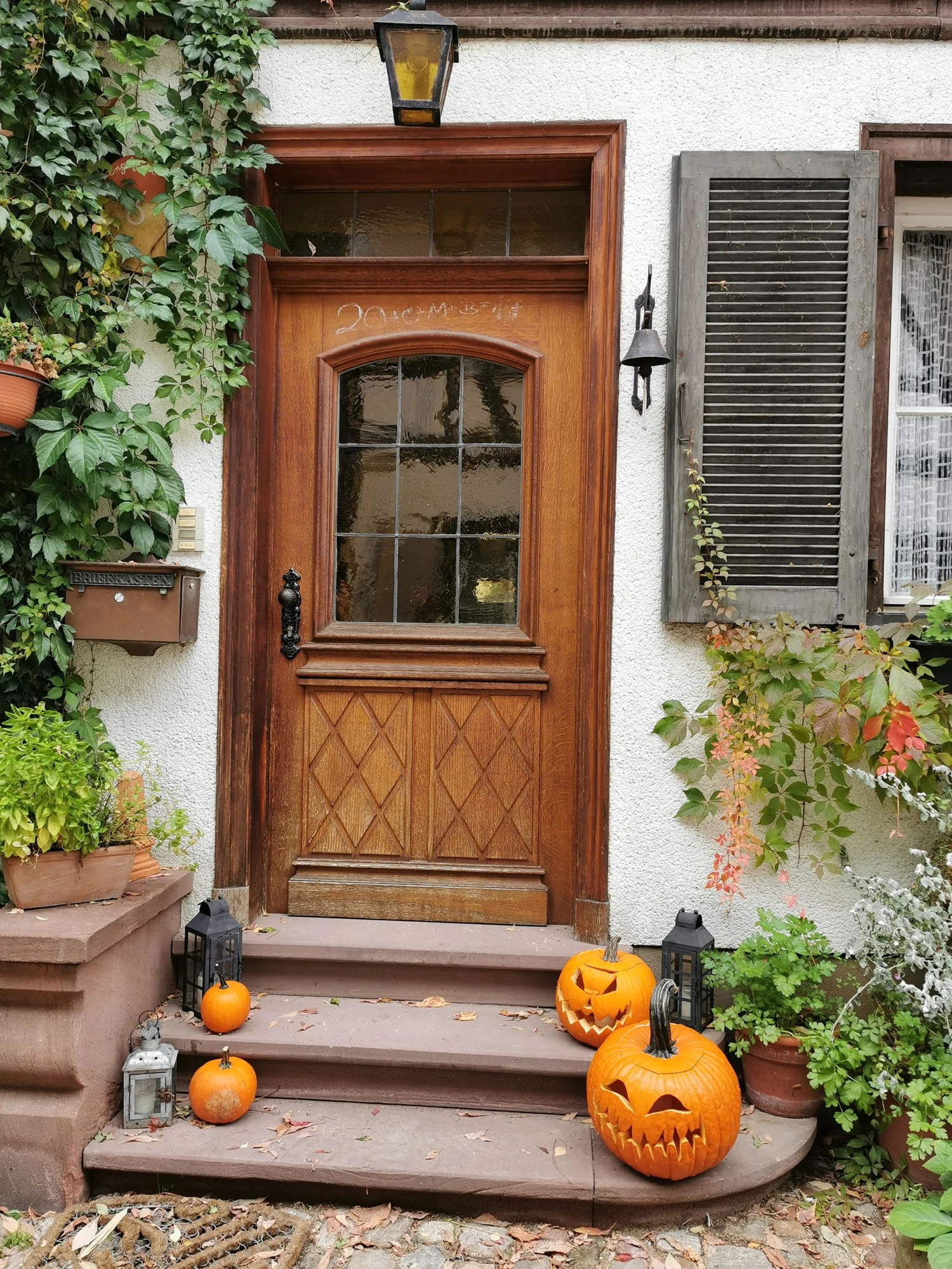 Full photograph of a wooden front door with pumpkins and lanterns arranged around the steps